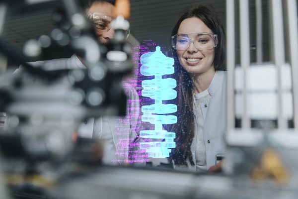 Smiling female and male engineers examining futuristic automation at laboratory