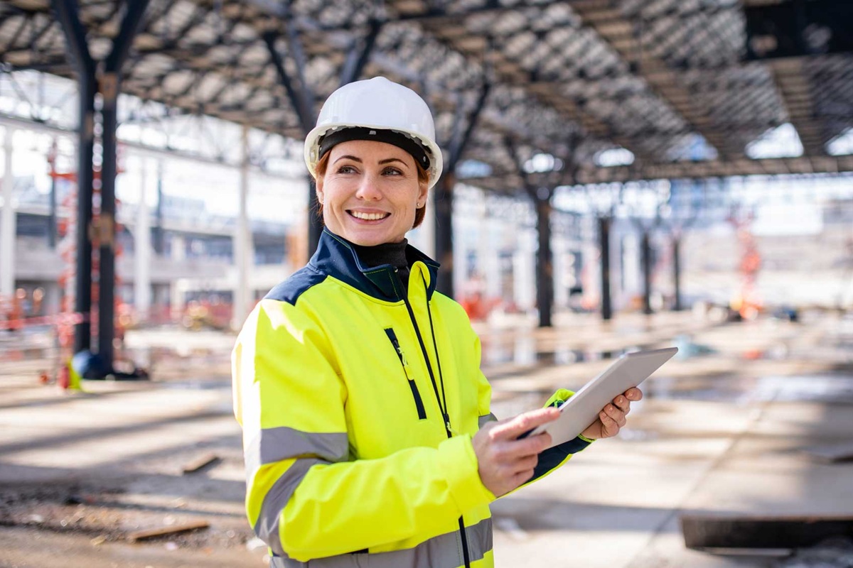 A woman engineer with tablet standing on construction site, working.
