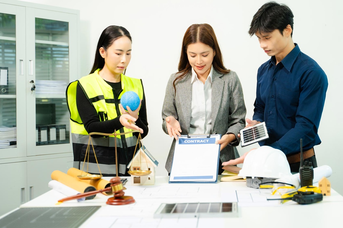Engineers, architects and legal professionals reviewing building plans with justice scale and gavel, symbolizing construction law, property regulation, contract